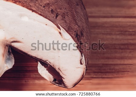 Close-up of a fresh mushroom cut in half. Directly above picture of a mushroom on a wooden chopping board.