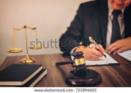 Gavel on wooden table and Lawyer or Judge working with agreement in Courtroom theme, Justice and Law concept.