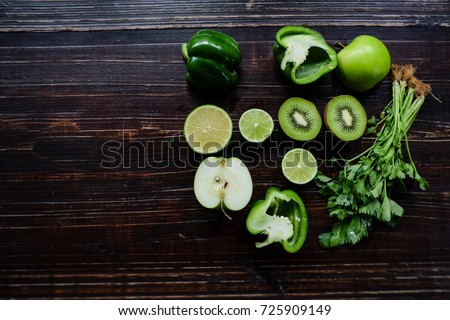 Colourfu green of very much fruits and vegetables on table. Chili, apple, kiwi, lemon, vegetables, pimento and more on wood table in the kitchen