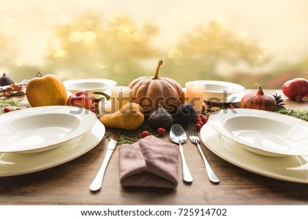 Four plates with cutlery and autumnal vegetables on wooden table
