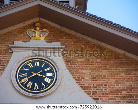 Vintage back face clock with gold Roman numerals on an old brick building.