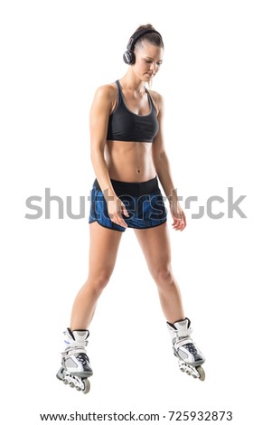 Roller skating woman braking or slowing down with roller skates and looking down. Full body length portrait isolated on white studio background.