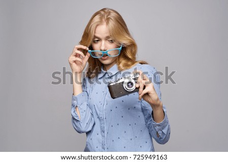 the photographer corrects his glasses looked at the old camera on a gray background                               