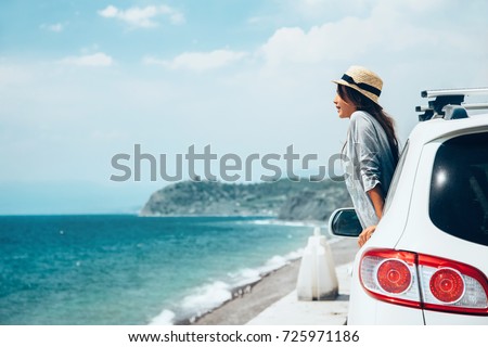 Rear view of pre teen child in car over sea view on summer roadtrip to the beach  Royalty-Free Stock Photo #725971186