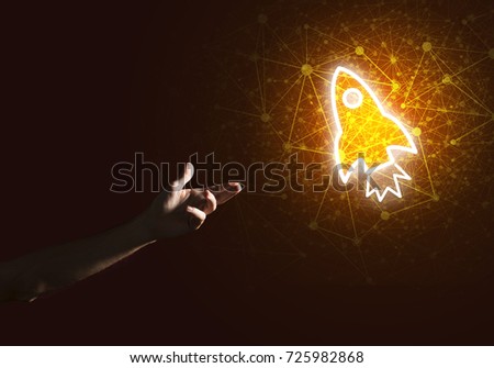 Rocket glowing icon and man hand on dark background