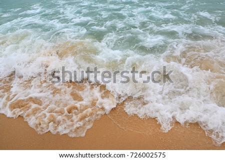 Ocean wave on sandy beach.