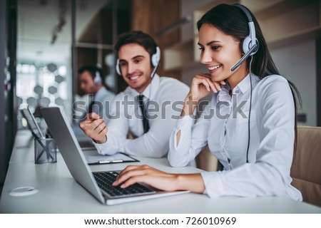 How can I help you? Beautiful call center workers in headphones are working at modern office. Royalty-Free Stock Photo #726010969