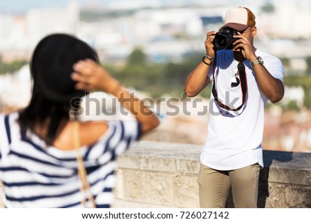 Portrait of handsome young man taking photo of his girlfriend on the street.