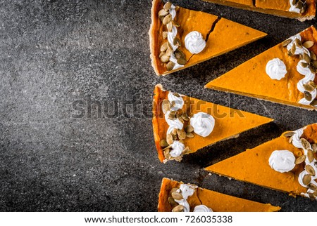 Traditional autumn dishes. Halloween, Thanksgiving. Set of cuted pieces of spicy pumpkin pie with whipped cream & pumpkin seeds on black stone table. Copy space top view