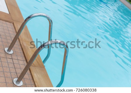 Outdoor poolside & stair handrail of a local rural calm blue swimming pool . Picture tilted intentionally for a special plate aspect