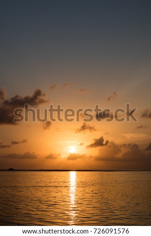Vertical picture of sunrise scene in Maldives with reflection on the water