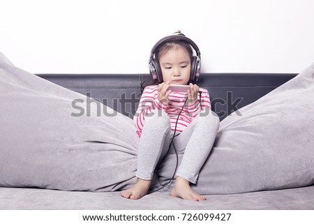 The pretty girl was listening to music on the sofa with earphones