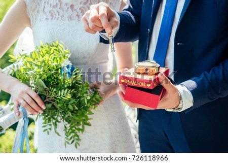 golden keys with a lock and a red box in the hands of the bride and groom with a lock and a red box