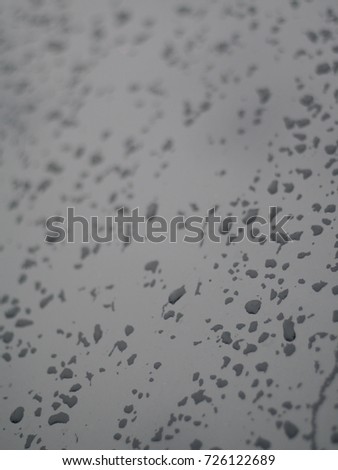rain drops on car windshield body smooth surface reflecting sunlight after rain selective focus blur background 