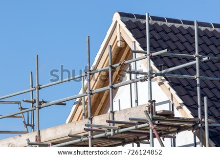 Modern house roof construction with scaffold pole platform. New build domestic building. Royalty-Free Stock Photo #726124852