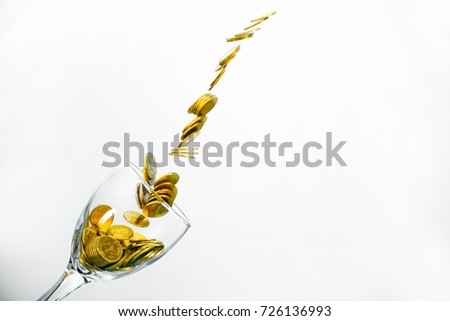 Golden coins splash in a glass of champagne on the wall background with copy space., saving money concept.