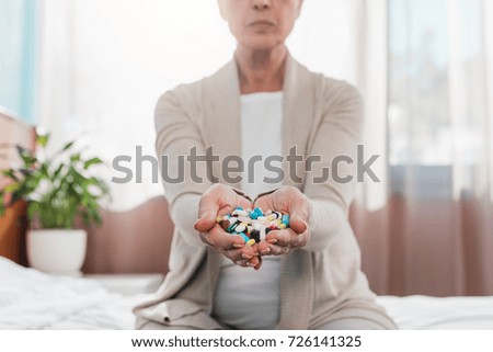 cropped shot of senior woman holding pills in hands