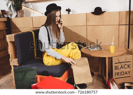 attractive woman with shopping bags talking on smartphone on black friday