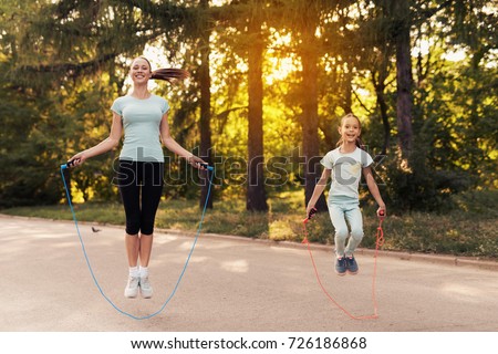 A woman and a little girl are jumping rope on the path in the park. They are having fun Royalty-Free Stock Photo #726186868