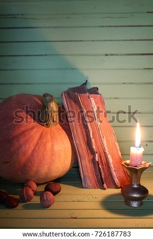 old book pumpkin and candle on wooden table
