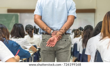 School exam room with teacher (invigilator) watching over students monitoring candidates taking examination in classroom having stress studying in class for passing admission test education concept Royalty-Free Stock Photo #726199168