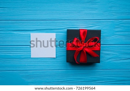 Greeting card, valentines letter, greeting card, photo frame and valentines black gift with red ribbon and bow on wooden background. Space for text. A gift for Birthday, Wedding, or Valentine's day.