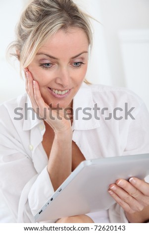 Blond woman using electronic tablet at home