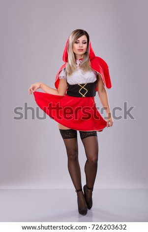 Woman dressed like Little Red Riding Hood over gray background. Studio shoot