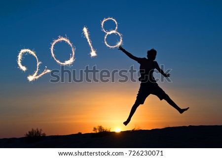 2018 written with sparkles, silhouette of a boy jumping in the sun