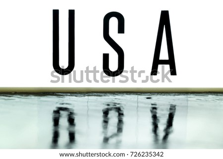 A light up board displays the phrase USA reflected on wet slate