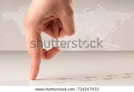 Female fingers walking with footsteps behind them and a world map in the background