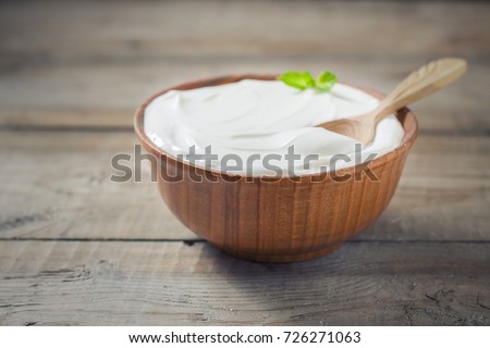 Greek yogurt in a wooden bowl on a rustic wooden table. Selective focus Royalty-Free Stock Photo #726271063