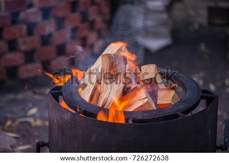 Burning bonfire with soft glowing flame and sparkles flying all around. Romantic summer evening. Preparing grill for barbecue party