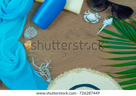 Assessary for travel go to the sea. Shawl blue,  Vintage hat, sunblock, Sunglasses, shells on old wooden floor. Have copy space, Top view, Flat lay.
