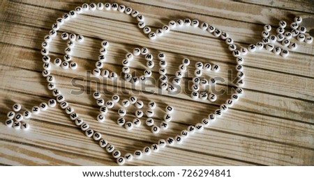 The phrase "I love you" big heart composed of white,round, plastic blocks on a wooden surface.