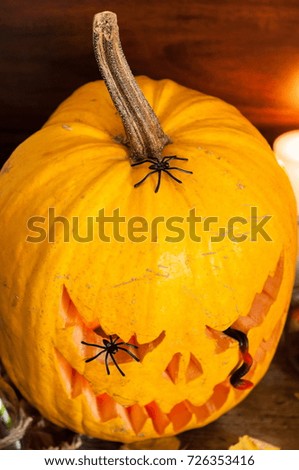 Closeup shot from above of artistic carved illuminated pumpkin for Halloween aside various decorations