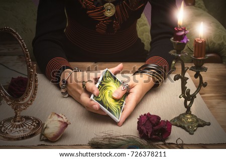 Tarot cards in fortune teller hands. Woman mixes tarot cards deck on wooden desk table. Reading future. Royalty-Free Stock Photo #726378211
