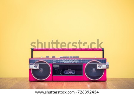 Retro outdated red portable stereo radio cassette recorder from 80s front yellow background. Vintage old instagram style filtered photo Royalty-Free Stock Photo #726392434