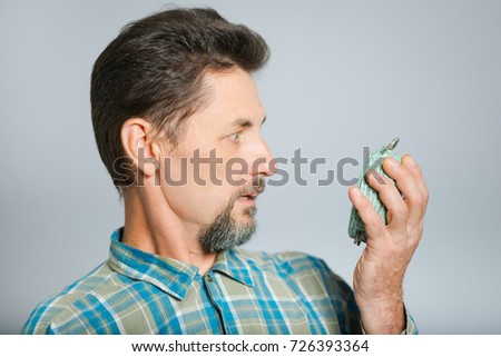 middle-aged man overslept and looks at alarm clock, isolated in studio on background