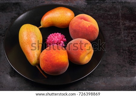 Pears and peaches on a black plate in retro style for a designer on a metal old background