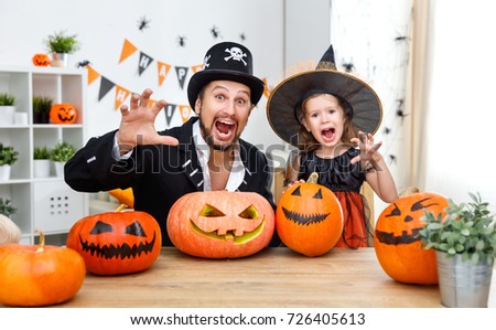 a happy family father and child daughter in costumes   for halloween at home

