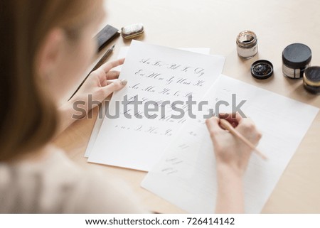 The girl is engaged in calligraphy. Hands of the girl and accessories for calligraphy.