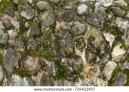 The texture of a wall of boulders covered with moss.
