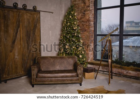 Dark loft interior. Christmas tree with a bunch of boxes with gifts. A beautiful brown leather sofa on a gray concrete wall background with a wooden door. Place for text. Background picture