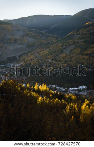 Vertical landscape view of Vail, Colorado during sunrise as autumn leaves start to change color. 