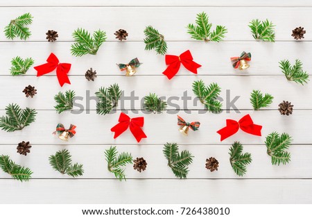 Christmas background and pattern. Top view of small bells and pine cones with green branches on white wood. Xmas and other winter holidays concept with copy space