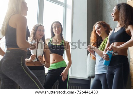 Girls in sportswear chatting before dancing class. Group of young fit female friends at sport club, pov. Active and healthy lifestyle concept