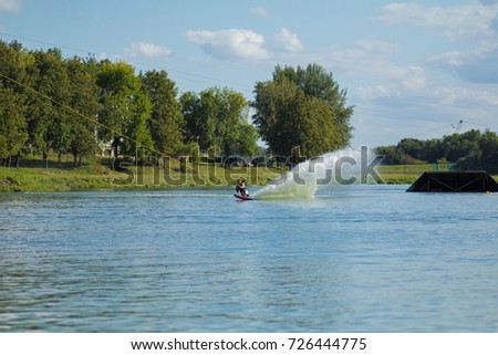 young male athlete glides on water skis on the waves on the lake