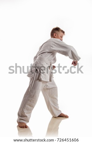 Boy blond athlete in white kimono performs wrestling fighting techniques on white background
