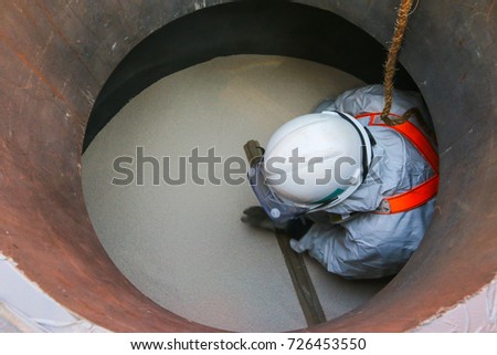 A contract worker is performing maintenance job in a process vessel. Royalty-Free Stock Photo #726453550